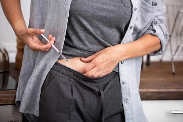 Vue recadrée de la femme malade debout dans la cuisine et faisant l'injection avec la seringue — Photo de stock