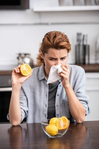 Frau mit laufender Nase niest in Gewebe und hält die Hälfte der leckeren Orange — Stockfoto