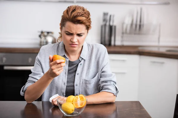 Недовольная женщина смотрит на половину апельсина — стоковое фото