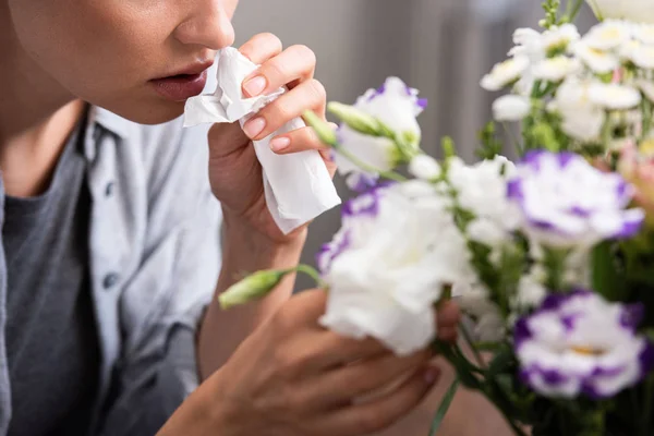 Cropped view of  woman with pollen allergy holding tissue and touching flowers — Stock Photo