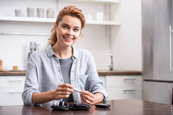 Selective focus of cheerful woman holding blood lancet — Stock Photo