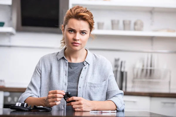 Attraktive Frau schaut in die Kamera, während sie zu Hause einen Bluttest macht — Stockfoto