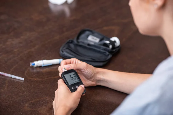 Selective focus of woman holding glucose monitor at home — Stock Photo