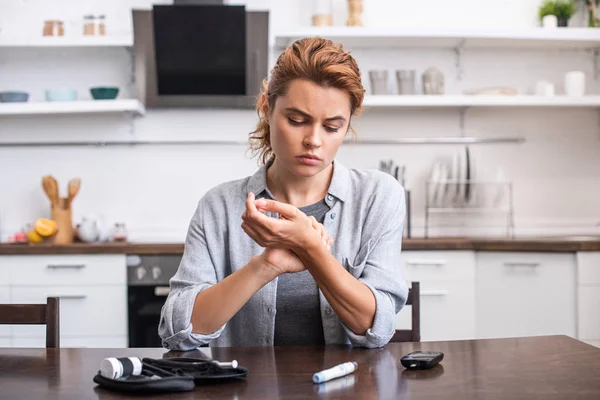 Attractive woman scratching hand near blood lancet at home — Stock Photo