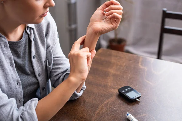 Cropped view of woman checking pulse near table — Stock Photo