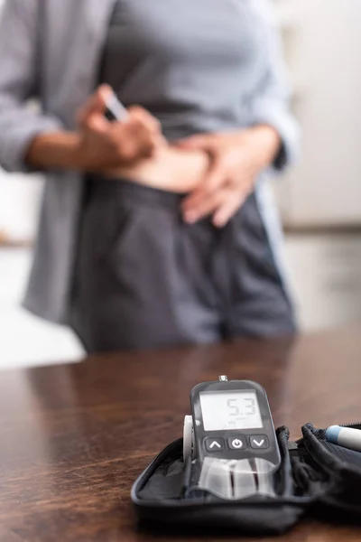 Selective focus of glucose monitor with numbers near woman — Stock Photo