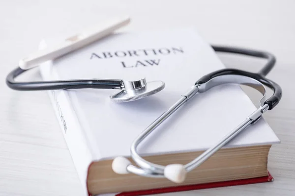 Selective focus of stethoscope on book with abortion law lettering near pregnancy test — Stock Photo