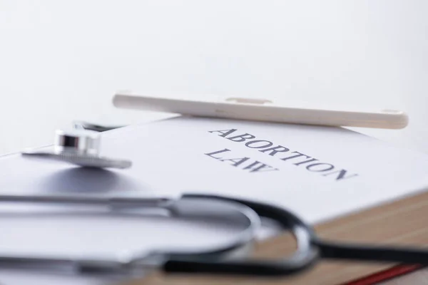 Selective focus of pregnancy test on book with abortion law letters near stethoscope — Stock Photo