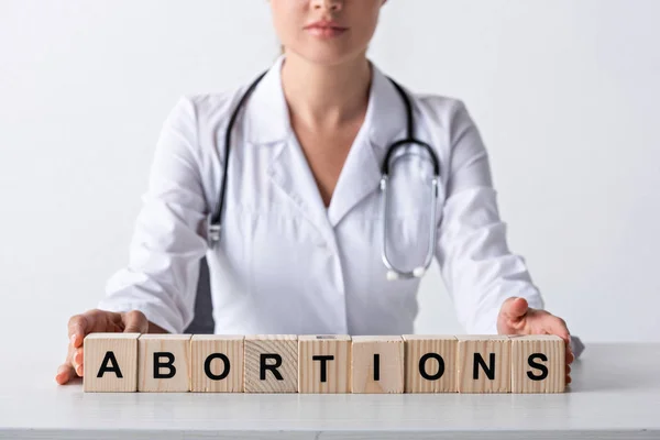 Vista recortada del médico tocando cubos con cartas de aborto - foto de stock