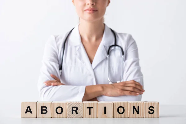 Vista recortada de médico con brazos cruzados cerca de cubos con cartas de aborto - foto de stock