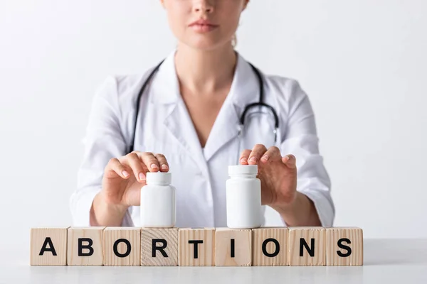 Vista recortada del médico tocando botellas en cubos con cartas de aborto - foto de stock