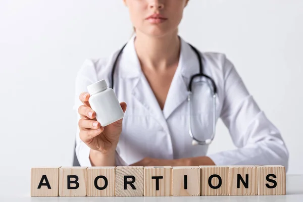 Vista recortada del médico sosteniendo botella cerca de cubos con cartas de aborto - foto de stock
