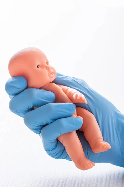 Cropped view of doctor in glove holding baby doll — Stock Photo