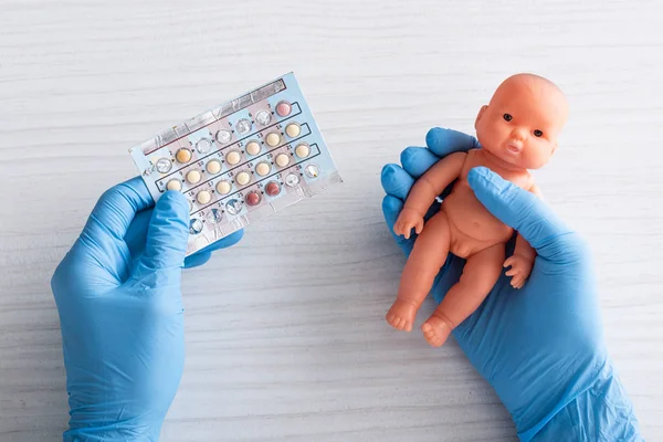 Vue du dessus du médecin en gants de latex tenant des pilules d'avortement et poupée dans les mains — Photo de stock
