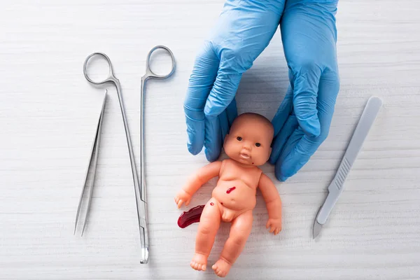 Vue du dessus du médecin en gants de latex bleu tenant une poupée avec du sang près des instruments médicaux — Photo de stock