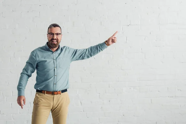 Uomo d'affari bello e sorridente in camicia che punta con il dito — Foto stock