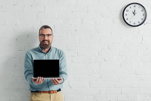 Красивий і усміхнений бізнесмен тримає ноутбук з копіювальним простором — стокове фото