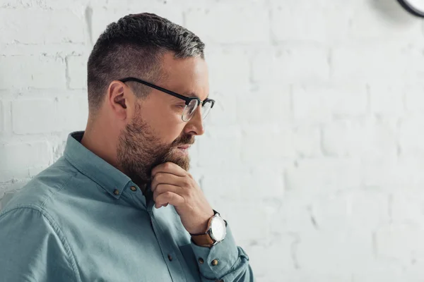 Vista lateral del hombre de negocios pensativo en camisa y gafas mirando hacia otro lado - foto de stock