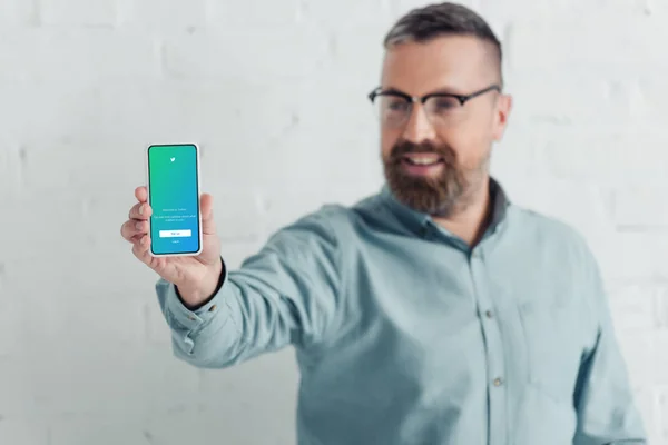 KYIV, UKRAINE - AUGUST 27, 2019: selective focus of handsome businessman holding smartphone with twitter app — Stock Photo