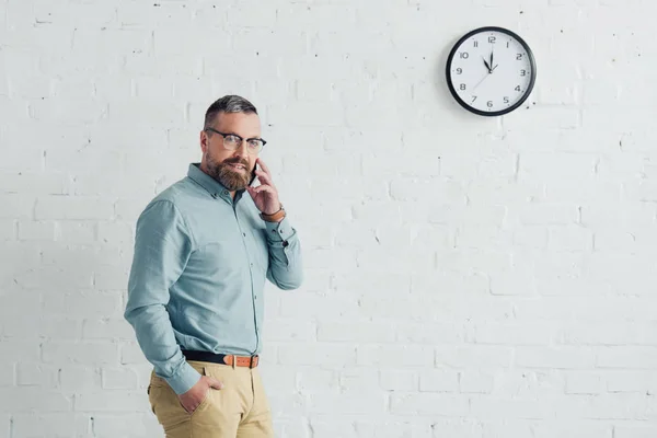 Schöner Geschäftsmann mit Hand in Tasche, der auf dem Smartphone spricht — Stockfoto