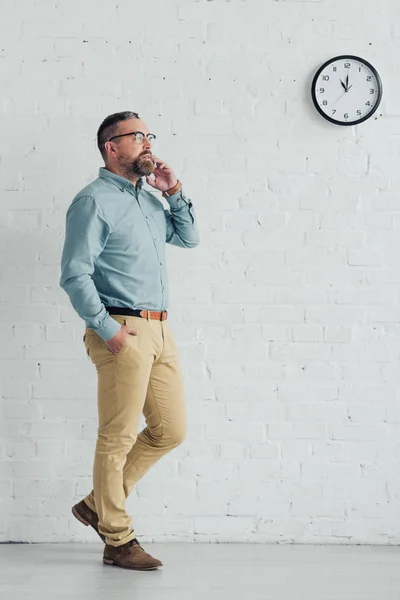 Schöner Geschäftsmann mit Hand in Tasche, der auf dem Smartphone spricht — Stockfoto