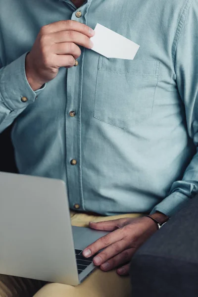 Cropped view of businessman in shirt holding blank card and laptop — Stock Photo