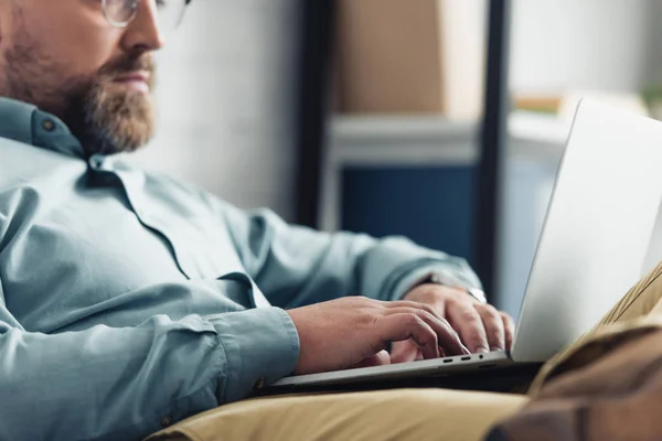 Vista recortada de hombre de negocios en camisa usando el ordenador portátil en la oficina - foto de stock