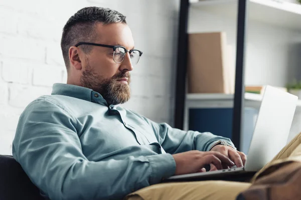 Bell'uomo d'affari in camicia e occhiali usando il computer portatile in ufficio — Foto stock