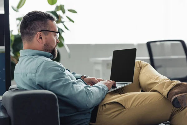 Красивий бізнесмен у сорочці та окулярах, використовуючи ноутбук в офісі — стокове фото