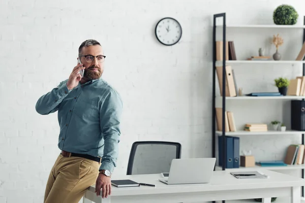 Bel homme d'affaires en chemise parlant sur smartphone et détournant les yeux — Photo de stock