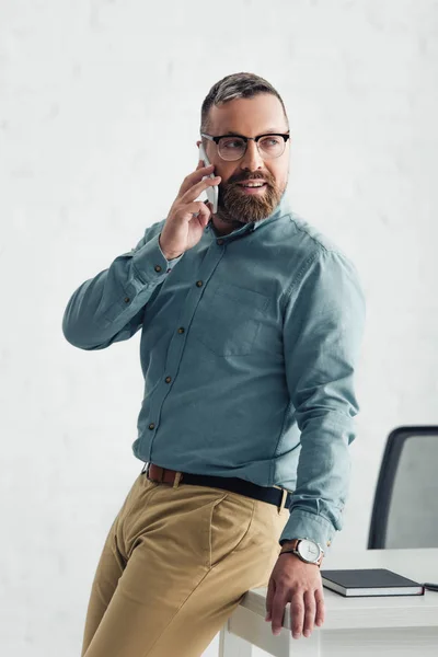 Hombre de negocios guapo en camisa hablando en smartphone y mirando hacia otro lado - foto de stock