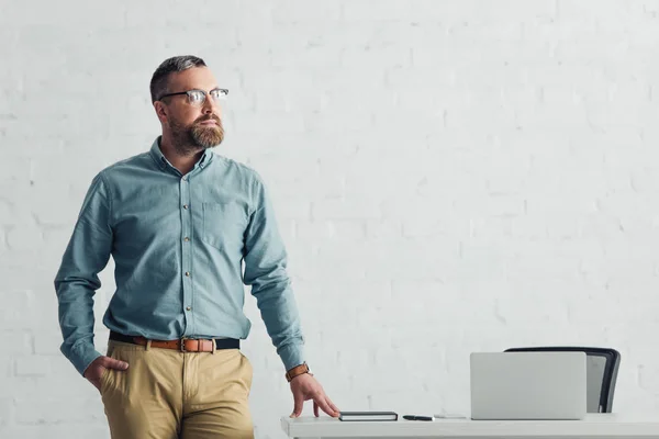 Schöner Geschäftsmann in Hemd und Brille, der im Büro wegschaut — Stockfoto