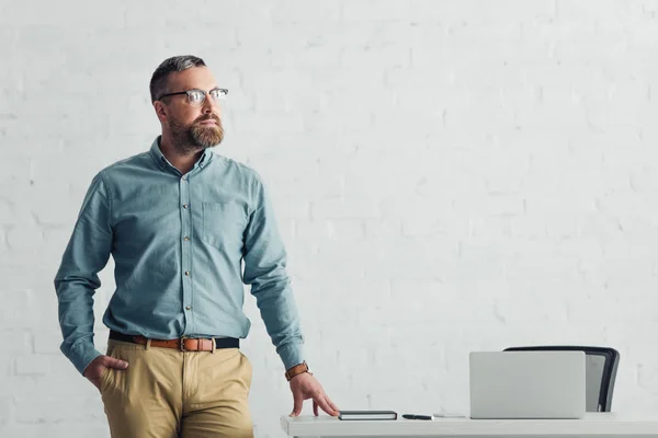 Handsome businessman in shirt and glasses looking away in office — Stock Photo