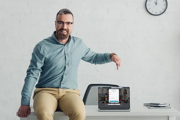 KYIV, UCRANIA - 27 de agosto de 2019: hombre de negocios guapo en camisa que apunta con el dedo a la computadora portátil con linkedin sitio web - foto de stock