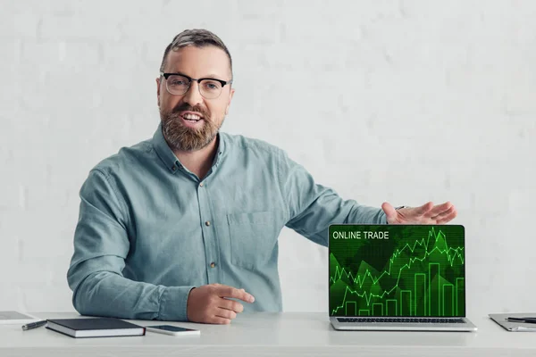 Handsome businessman in shirt holding laptop with online trade website — Stock Photo