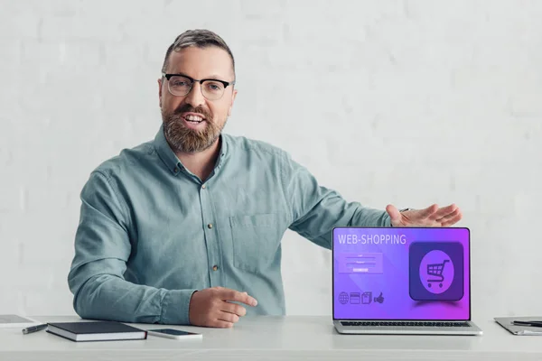 Handsome businessman in shirt holding laptop with web-shopping website — Stock Photo