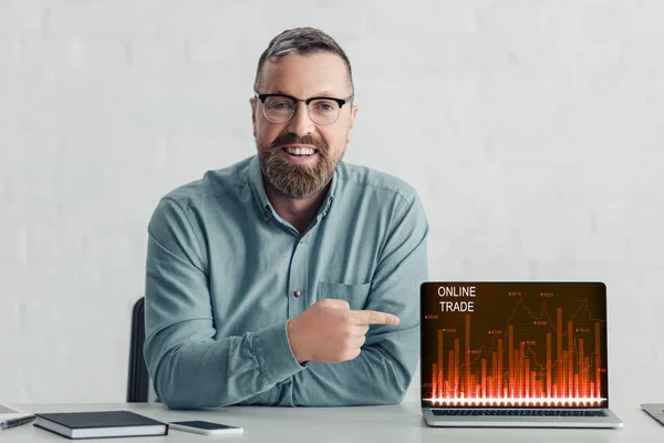 Hombre de negocios guapo en camisa que apunta con el dedo a la computadora portátil con el sitio web de comercio en línea - foto de stock