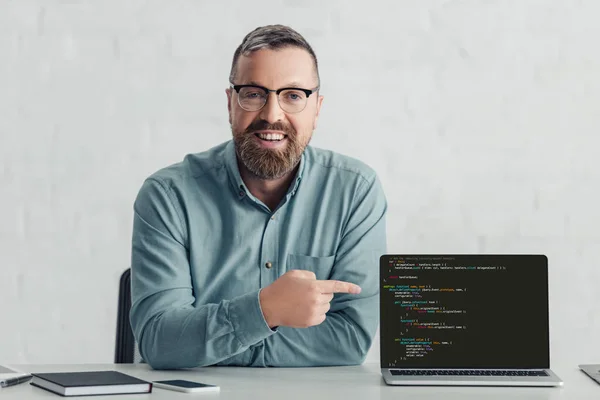 KYIV, UKRAINE - 27 AOÛT 2019 : bel homme d'affaires en chemise pointant du doigt sur un ordinateur portable avec un site Web — Photo de stock