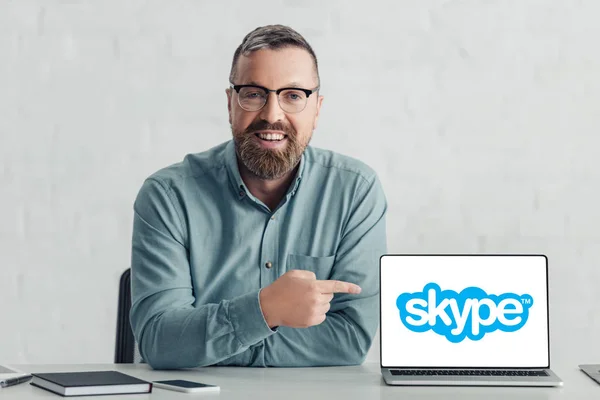 KYIV, UKRAINE - 27 de agosto de 2019: belo homem de negócios de camisa apontando com o dedo para o laptop com logotipo skype — Fotografia de Stock