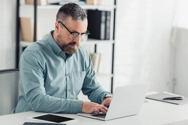 Schöner Geschäftsmann in Hemd und Brille mit Laptop im Büro — Stockfoto
