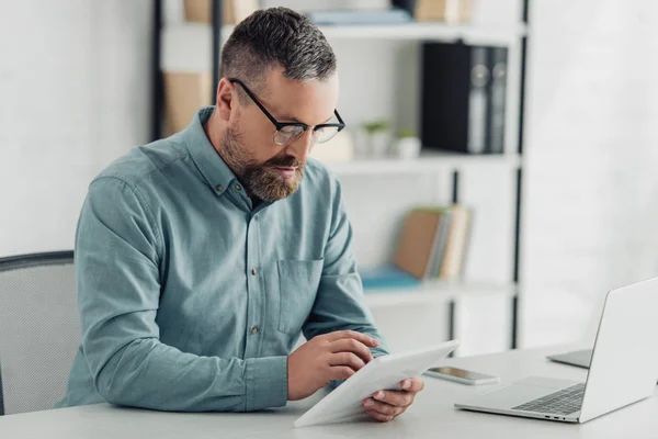 Bell'uomo d'affari in camicia e occhiali con tablet digitale in ufficio — Foto stock