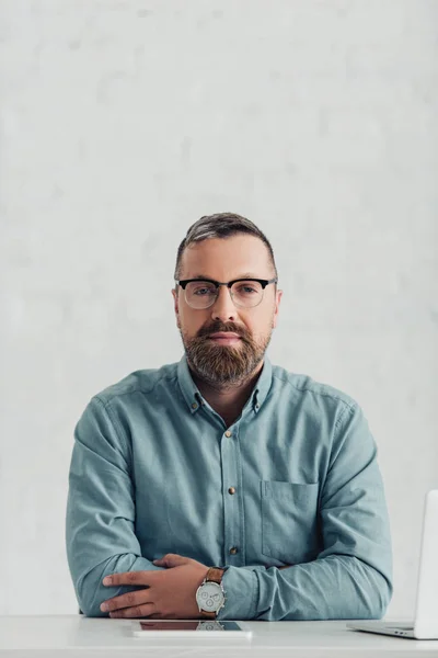 Schöner Geschäftsmann in Hemd und Brille, der im Büro in die Kamera schaut — Stockfoto