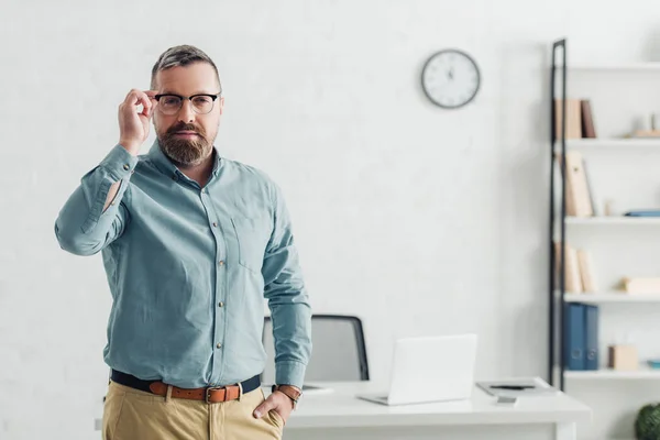 Handsome businessman in shirt and glasses looking at camera in office — Stock Photo