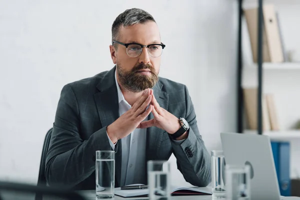 Handsome businessman in formal wear and glasses looking away in office — Stock Photo