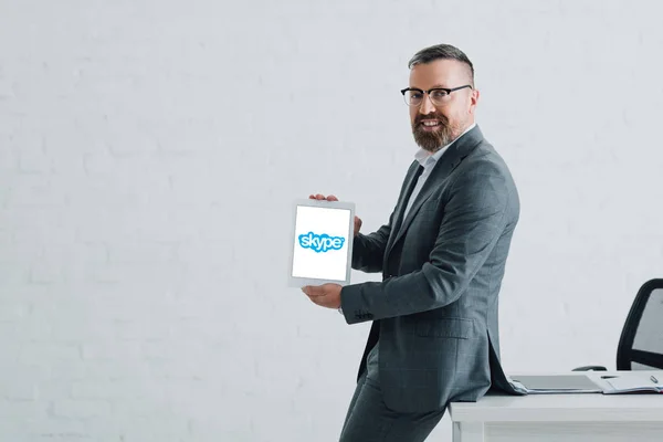 KYIV, UCRAINA - 27 AGOSTO 2019: bell'uomo d'affari in abbigliamento formale con tablet digitale con logo skype — Foto stock