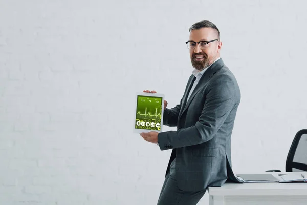 Handsome businessman in formal wear holding digital tablet with health website — Stock Photo