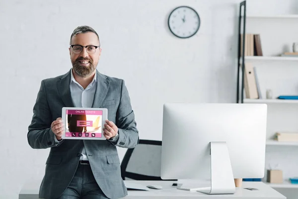 Guapo hombre de negocios en ropa formal celebración tableta digital con entradas en línea sitio web - foto de stock