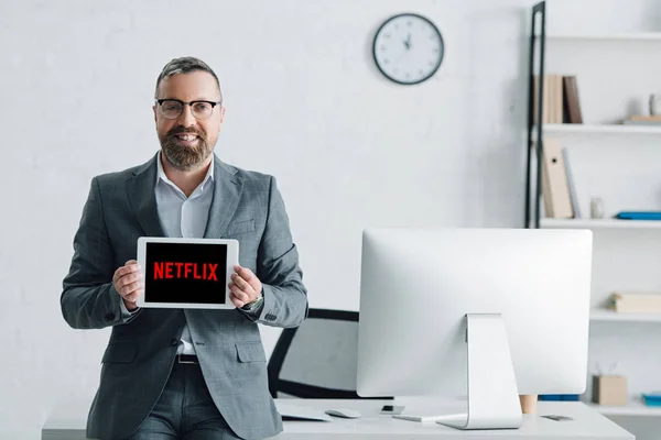 Kyiv, ukraine - 27. August 2019: gutaussehender Geschäftsmann in formeller Kleidung mit digitalem Tablet mit Netflix-Logo — Stockfoto