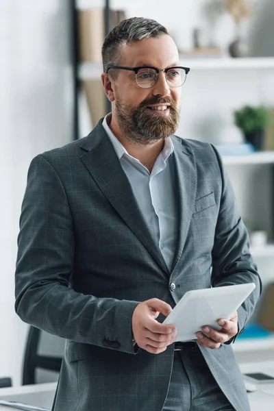 Homem de negócios bonito em desgaste formal usando tablet digital no escritório — Fotografia de Stock