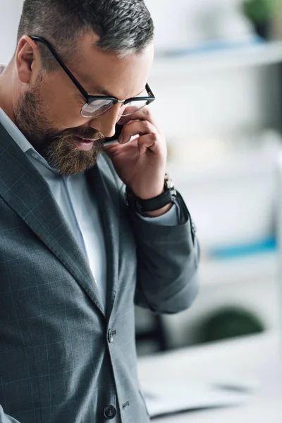 Красивий бізнесмен в формальному одязі говорить на смартфоні в офісі — стокове фото